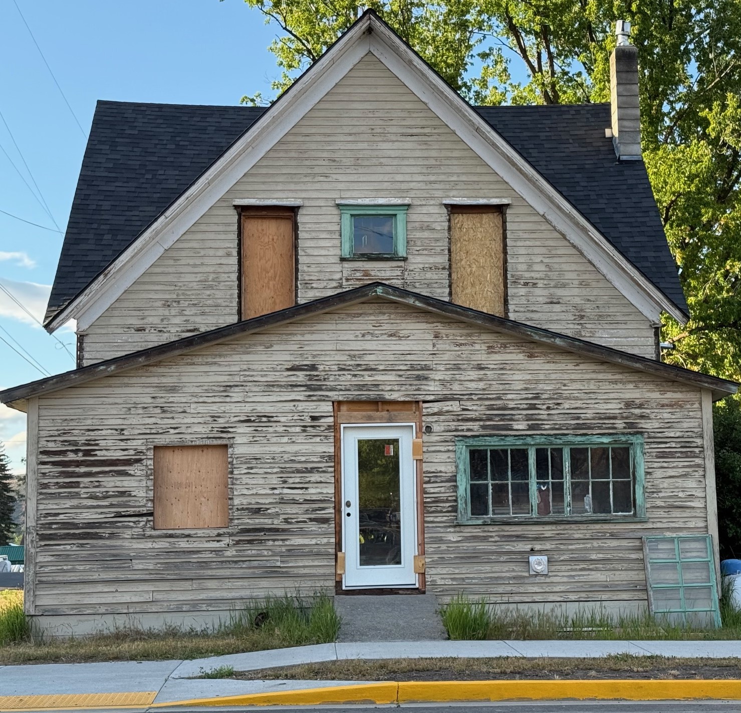 Before exterior renovation of Oregon home with rotten siding and windows needing complete replacement.